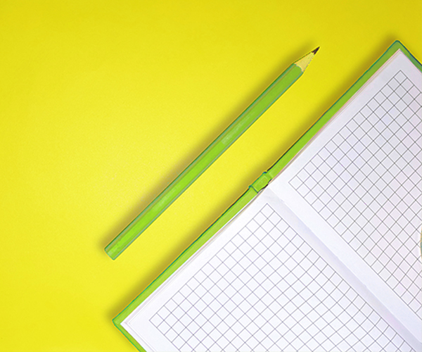 green-notebook-and-pencil-on-yellow-background
